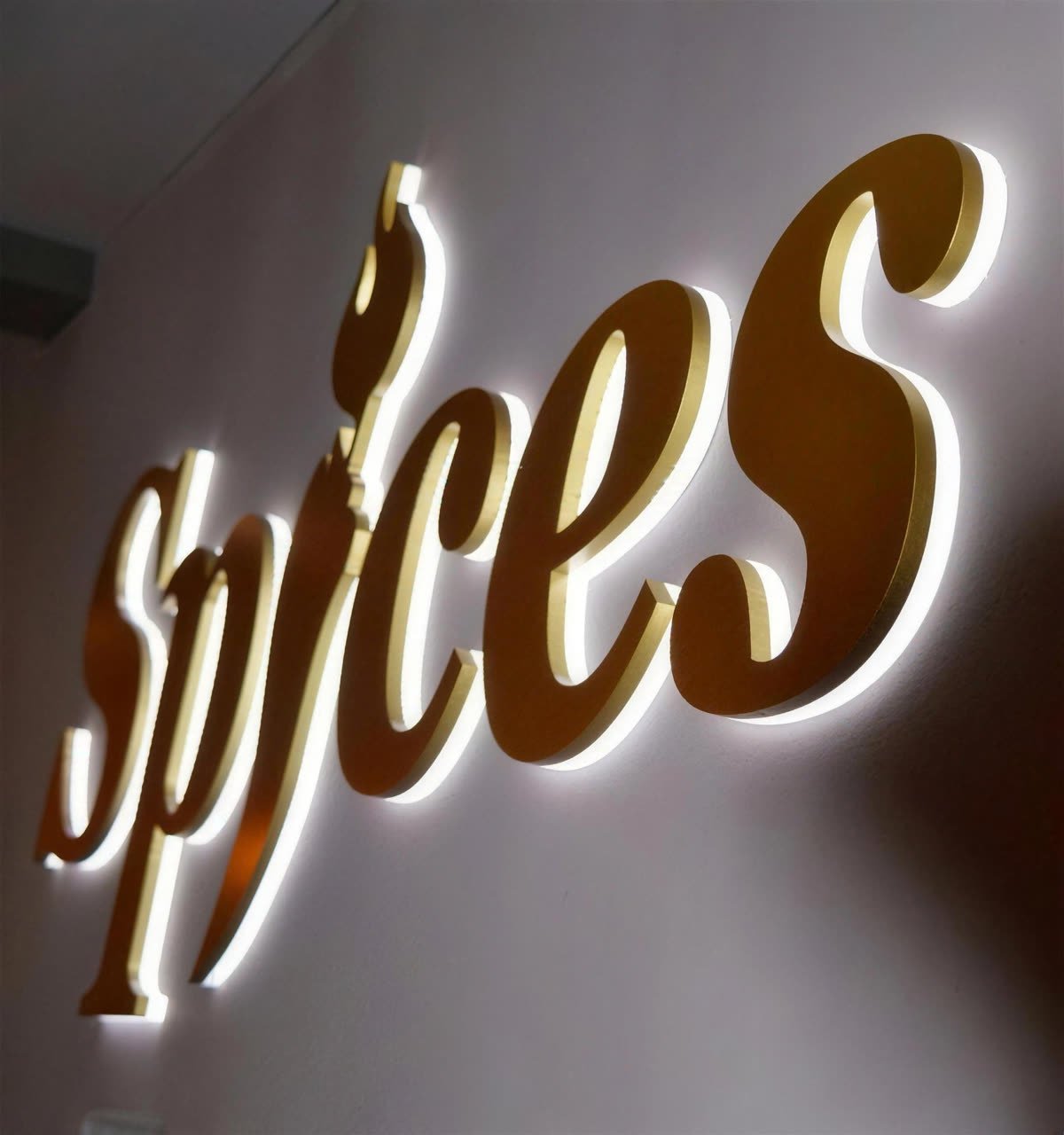 Het gouden Spices-logo aan de wand van het restaurant