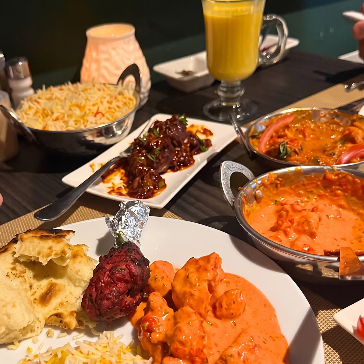 Een gedekte tafel bij Spices met butter chicken, naan, rijst en tandoori